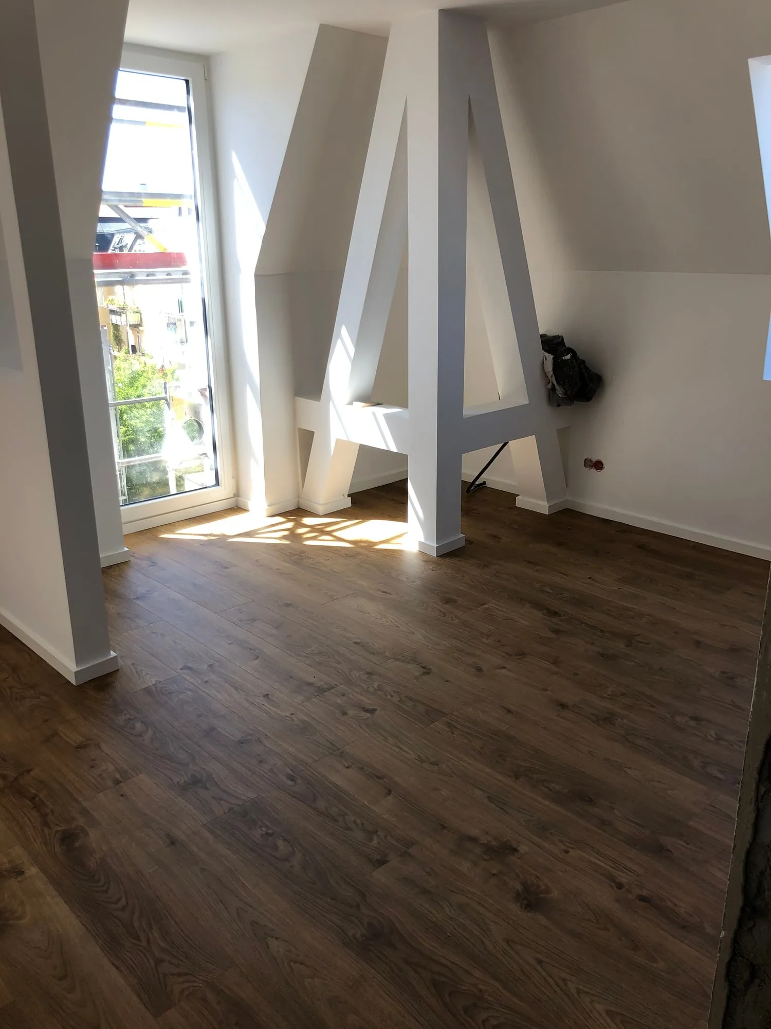 Dunkler Dielenboden in einem Dachgeschoss mit weißen Holzstützen