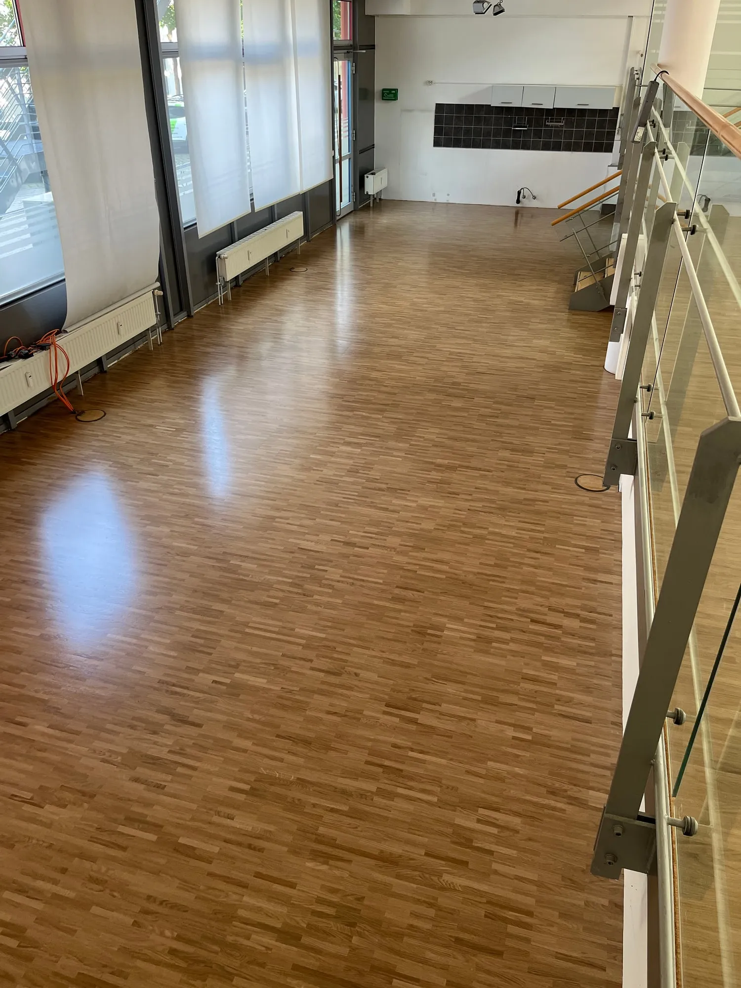 Parkettboden aus Eiche in einem langen Raum mit Fensterfront und Glasgeländer