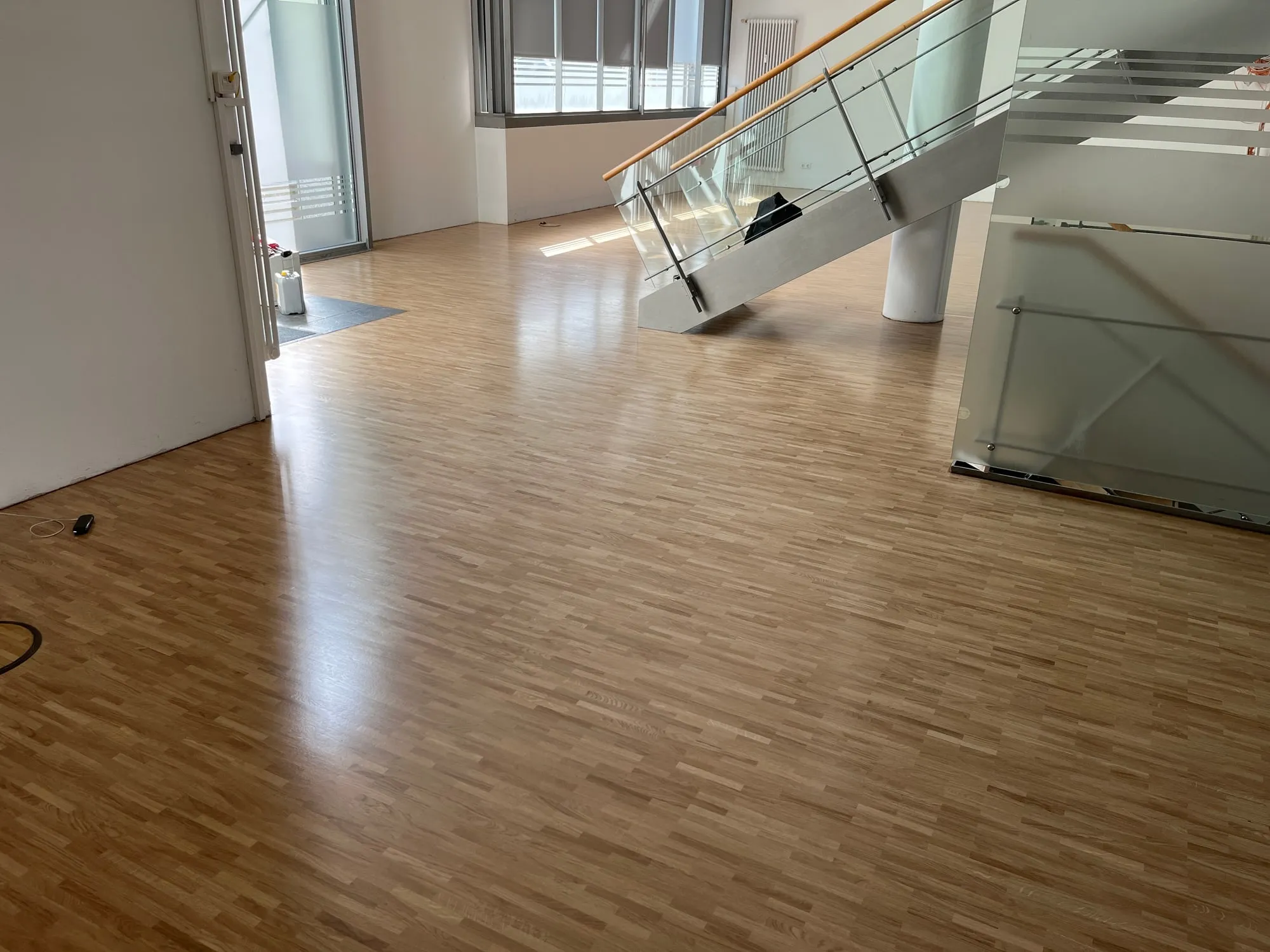 Parkettboden aus Eiche in einem hohen Raum mit Glasgeländer
