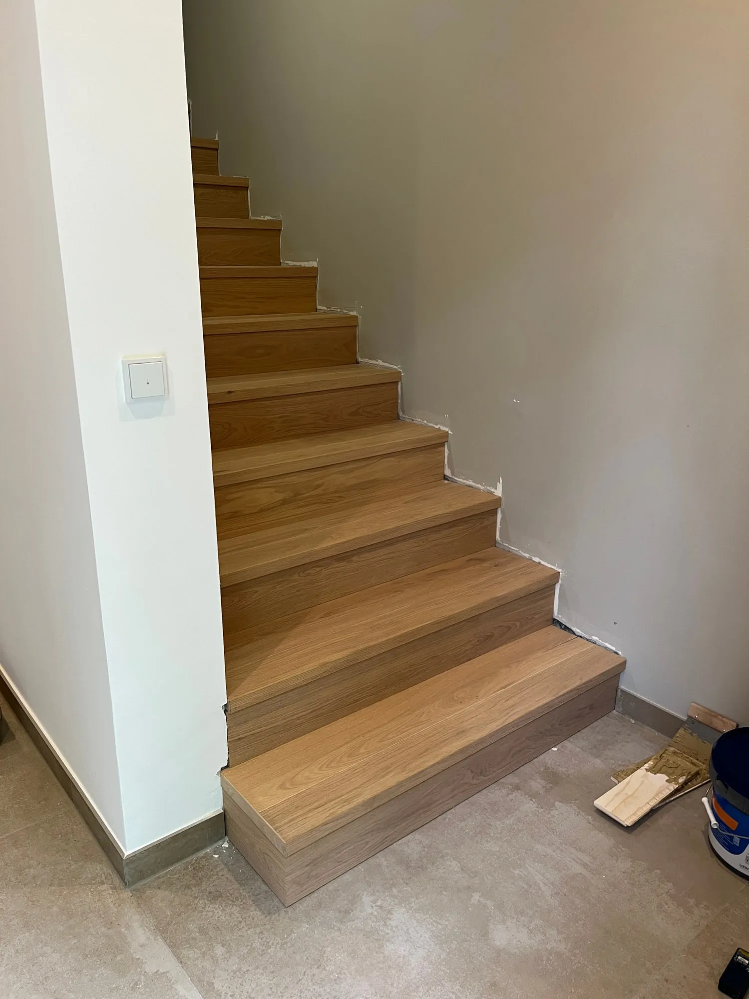Treppe mit Stufen aus Eiche entlang einer weißen Wand